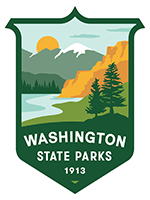 Washington State Parks Logo, a dark green border in the shape of a badge, the interior of the border is a natural scene in a modern and simple graphic design style. There are dark green trees and an orange hill next to the shore and a body of water with more hills and a mountain in the background with an orange sun partially behind the mountain.